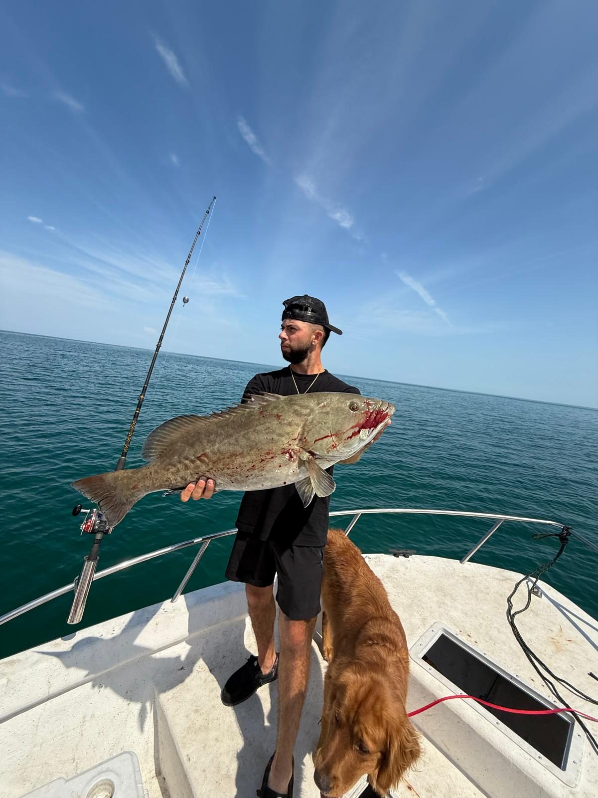 A member holding his catch with his golden retriever aboard